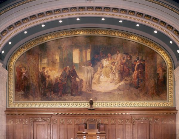 Dominating the front of the Assembly Chamber, in the Wisconsin State Capitol, is the mural, "Wisconsin," by Edwin Howland Blashfield. A woman representing Wisconsin is surrounded by three women representing the three bodies of water surrounding the state, Lake Michigan, Lake Superior, and the Mississippi River.
