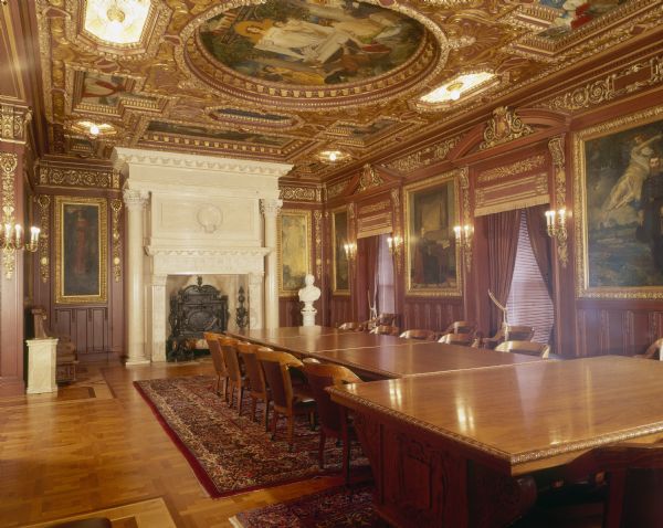 Governor's Conference Room, in the Wisconsin State Capitol. The room was designed in the Venetial Renaissance style. The ceiling and mural paintings are the work of Hugo Ballin. The fireplace at the north end of the room is hand-carved of Italian Botticino marble, and flanked on each side by a Corinthian column.