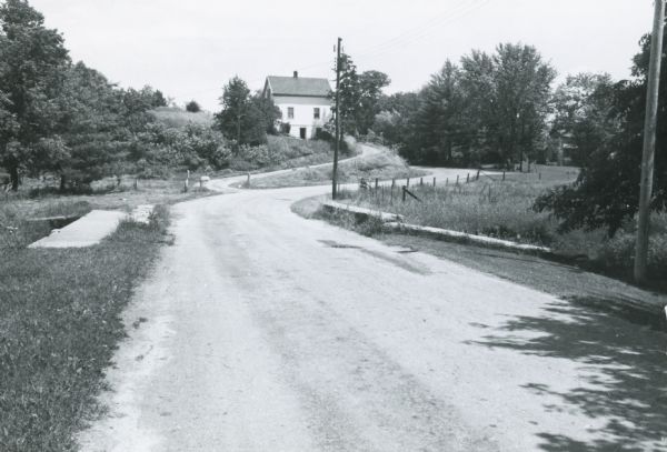 View of rural Monroe County Highway P, looking east toward a house in the curve of the road.