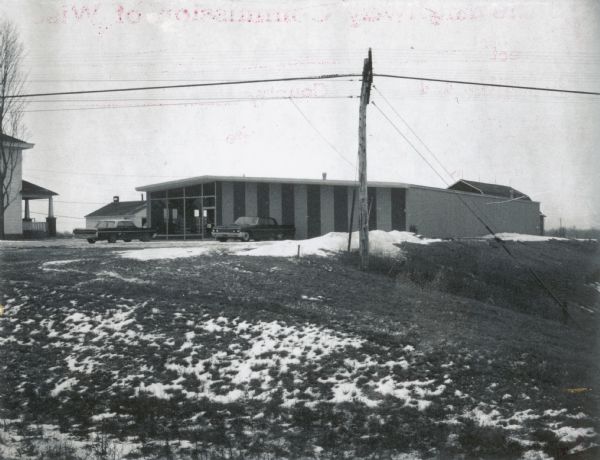 View of a metal commercial building with a house, probably a farm house, immediately to its left. These buildings lay on the planned route of the Wausau Beltline.