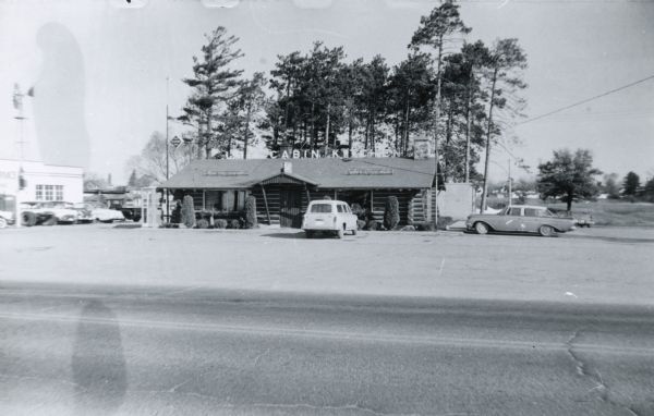 The Log Cabin Kitchen restaurant located along Business 51 in Schofield.  The building was constructed to resemble a log cabin. A few cars can be seen parked near the building.