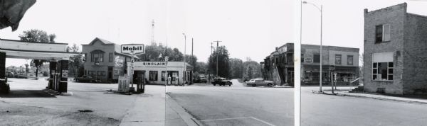 Intersection in Fremont, Wisconsin, showing two service stations.  The panorama was created by the Department of Transportation by taping together three prints.  However, the image on the right was incorrectly joined.  In the scan the image is properly placed, although leaving a blank between two photographs.