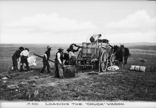 View of cowboys loading the chuck wagon on the range in Montana. Caption reads: "Loading the 'Chuck' Wagon."