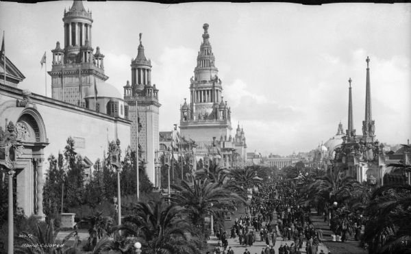 Elevated view of crowd on Palm Avenue at the Panama-Pacific Exposition in San Fransisco, California, 1915. Several ornate buildings can be seen near the crowded avenue. The exposition was the worlds fair held in 1915, and was the world celebration of the completion of the Panama Canal. The "Tower Of Jewels" can be seen on the left. The tower was the centerpiece building of the exposition.