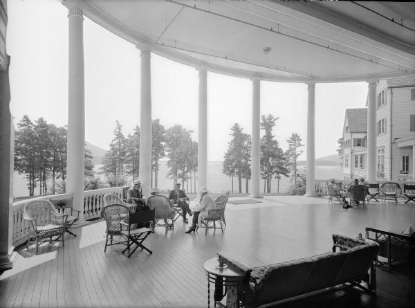Patrons are shown relaxing on the veranda of the Sagamore Hotel in Lake George, New York. The Sagamore opened in 1883 with luxurious and spacious accommodations that attracted a select, international clientele. Twice damaged by fire, in 1893 and 1914, the Sagamore was fully reconstructed in 1930.