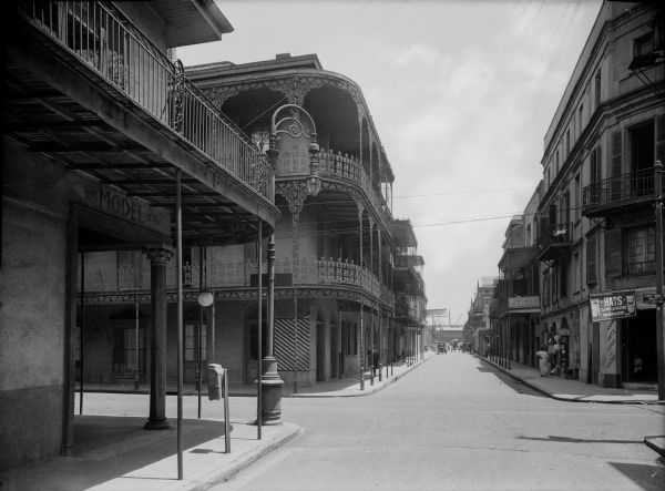 Royal Street view of the French Quarter. Store signs display, "The Model Store"; "Hats"; and "Peretti".