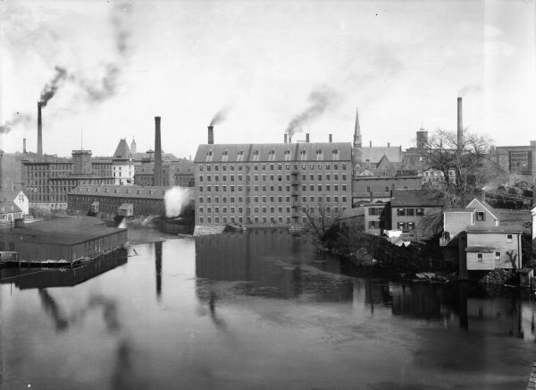Elevated view across river toward several factories with smokestacks.