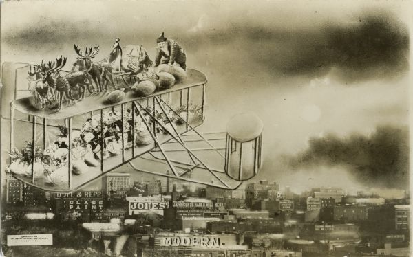 Photomontage of Santa Claus and his reindeer riding on the top wing of a bi-plane. More sacks of toys and wrapped gifts are on the lower wing. Buildings and skyline of a large city are visible below.