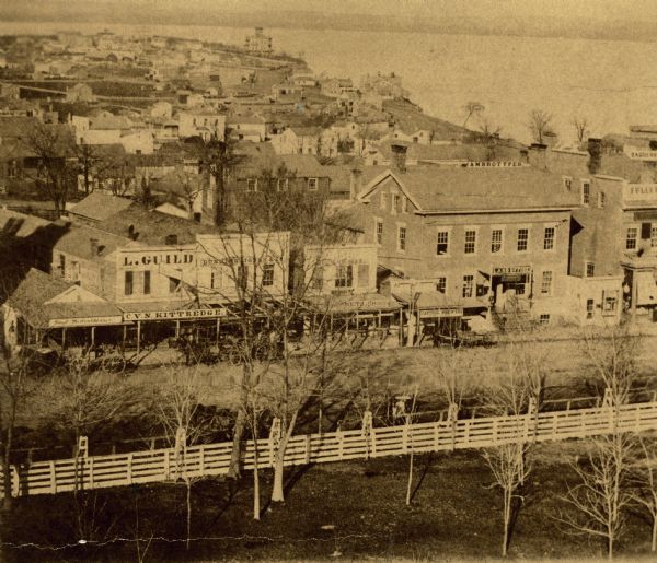Madison's Pinckney Street, with the Capitol Park in the foreground and Farwell's octagon house and Lake Monona in the distance.  This view has been variously identified in the past: Thwaites' "Story of Madison" identifies it as copied from from a daguerreotype taken from the rotunda of the Capitol, 1856, while this original print is labeled 1859 and indicates that it was enlarged from an ambrotype. It is a variant of Image ID: 26867, showing more of the U.S. Hotel, and was therefore taken by John S. Fuller.