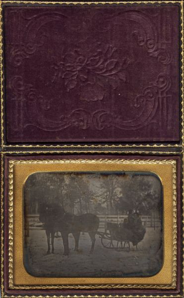 Quarter plate daguerreotype of Elias Dean, an early Madison businessman, riding in a sleigh drawn by two horses with his wife Sarah Fairchild Dean and young daughter. In the background is a white fence and a shadowy structure that may be the first Madison capitol.