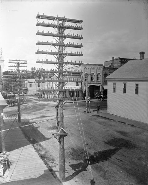 Elevated view of telephone poles loaded with wires. Store of A.F. Werner identifiable.