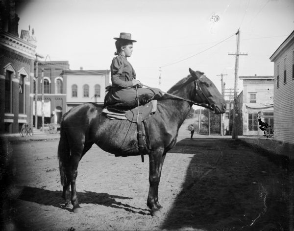 Woman posing sidesaddle on a horse.