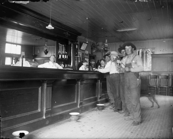 Men drinking at a bar, with a faint outline of a dog's hindquarters.