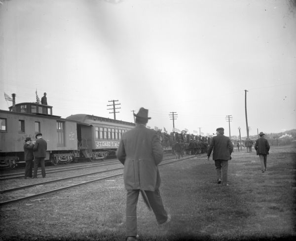 Men approaching a train at the railroad depot carrying farm machinery from the J.I. Case Company.	