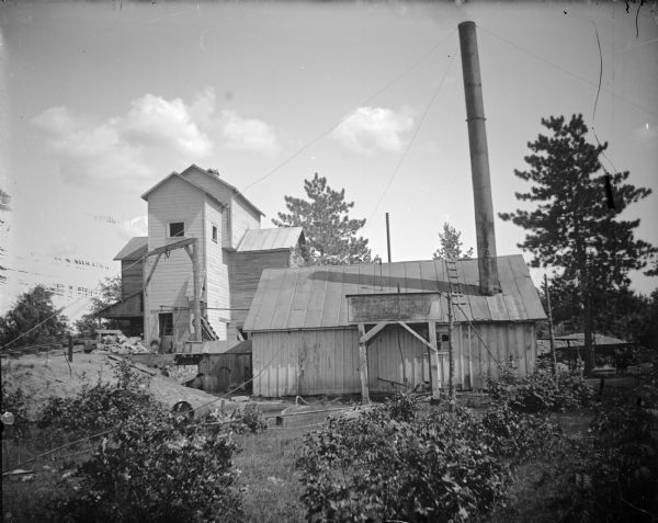 Grain elevator near the railroad station on the left, and a rock crusher on the right for crushing granite for street paving.