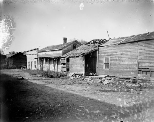 Dilapidated buildings, one has a photograph gallery sign, possibly North Second Street. The building with the photograph gallery sign may be the first studio of Charles J. Van Schaick.