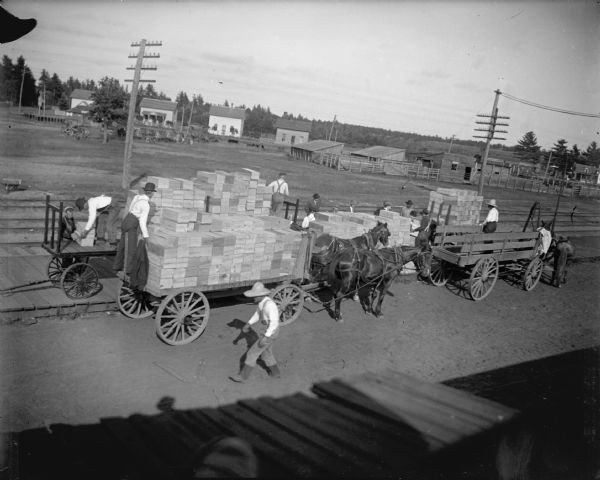 Elevated view of men unloading boxes at the railroad station, probably strawberries and blueberries.