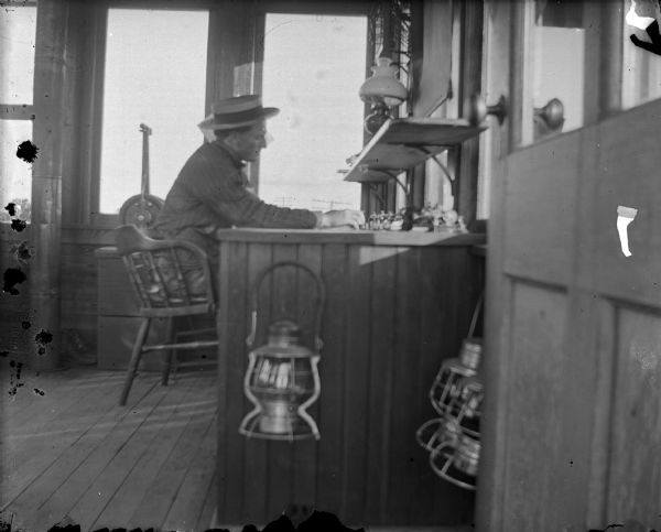 Man, possibly Milton J. Harphold, sitting at a telegraph desk in the railroad switch tower.