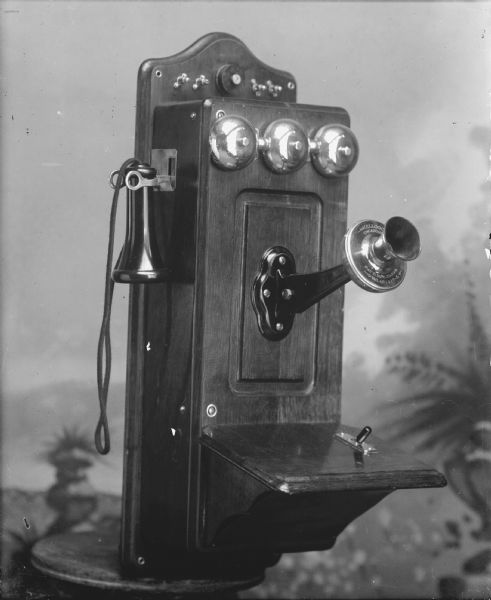 Kellogg box telephone in front of a painted backdrop. Patented November 26, 1901.