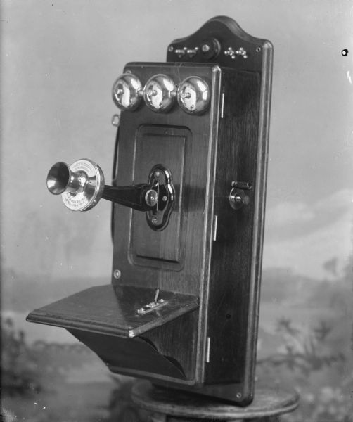 Kellogg box telephone in front of a painted backdrop. Patented November 26, 1901.