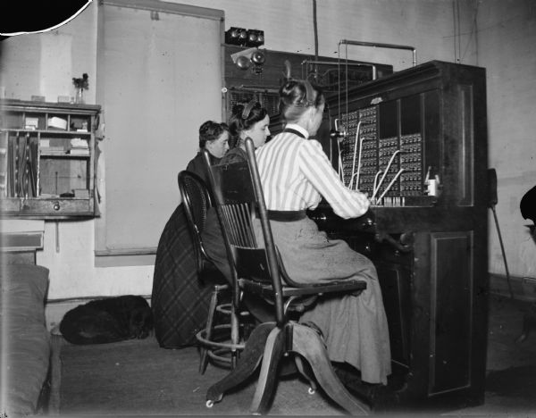 Three female telephone operators working at the telephone switchboard.