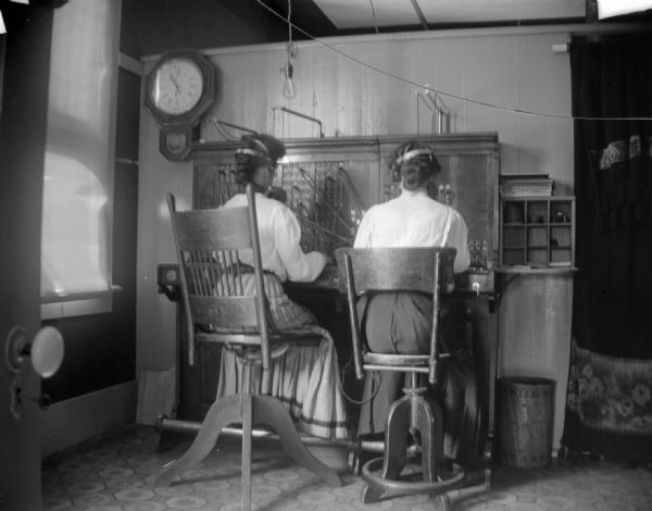 Two female telephone operators working the telephone switchboard.