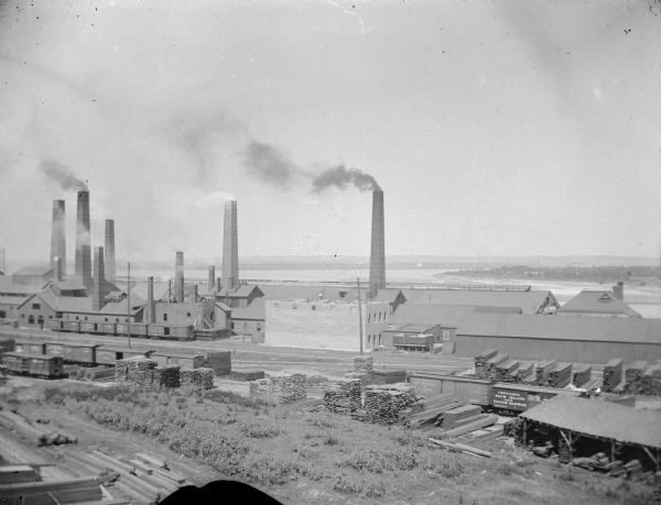 Brick plant, possibly the one at Haley, six to seven miles up the river from Black River Falls. May also be a sawmill, as piles of lumber are in the foreground.
