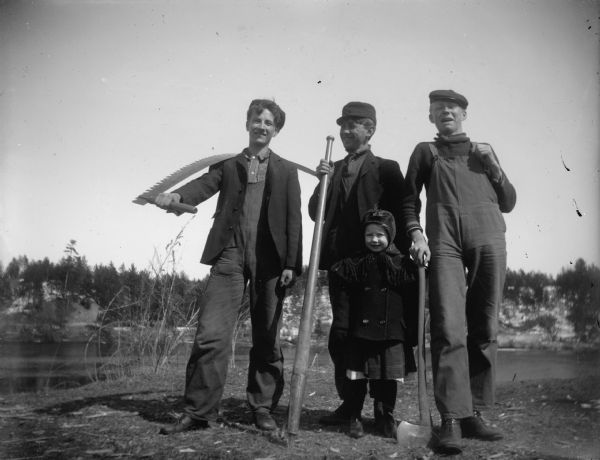 Three lumberjacks posing with their tools and a little girl. From right to left are Jule "Buck" Allen," Neil Hauger, and unidentified.