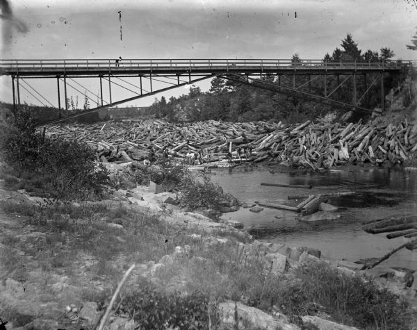 Men working to break up a log jam under the Hatfield Wagon Bridge. This is the original Hatfield Bridge, destroyed when the Hatfield Dam failed in the flood of 1911.