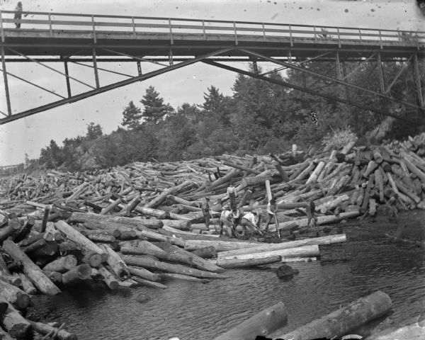Men working to break up a log jam under the Hatfield Bridge. This is the original Hatfield Bridge, destroyed when the Hatfield Dam failed in the flood of 1911.