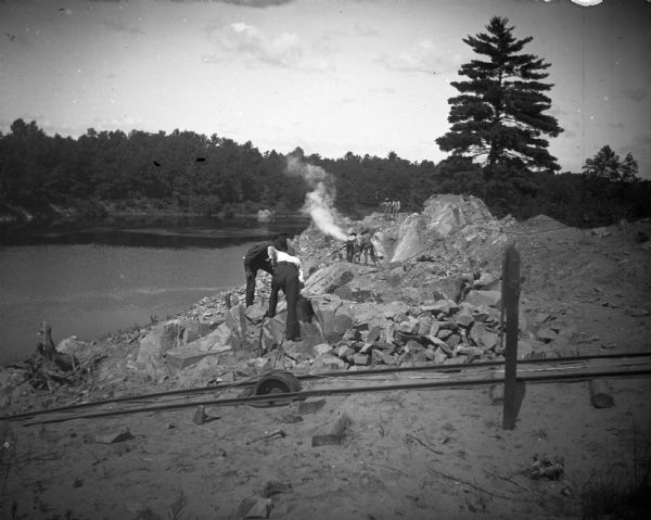 Men working along the shore of the river, probably in connection with the rock crushing works, one-half mile south of the York Iron Company on the Black River north of Black River Falls.