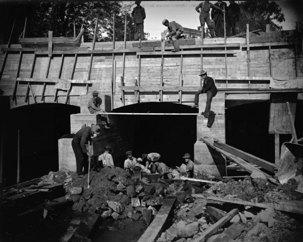 Men working on the bulkhead above the powerhouse and the powerhouse flume.