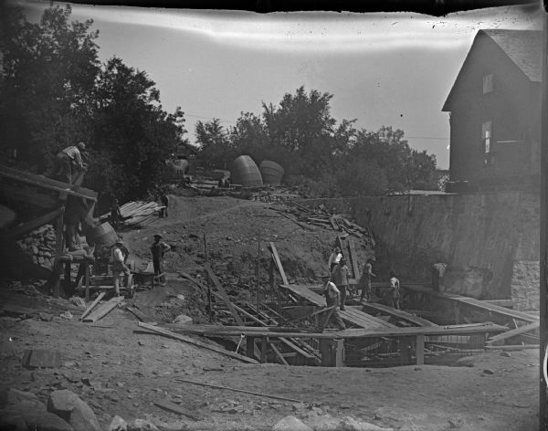 Men working on the foundation of a building, possibly laying a foundation for the post-flood business district dam.