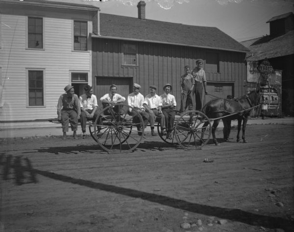 Six men and a boy sitting on a wagon.