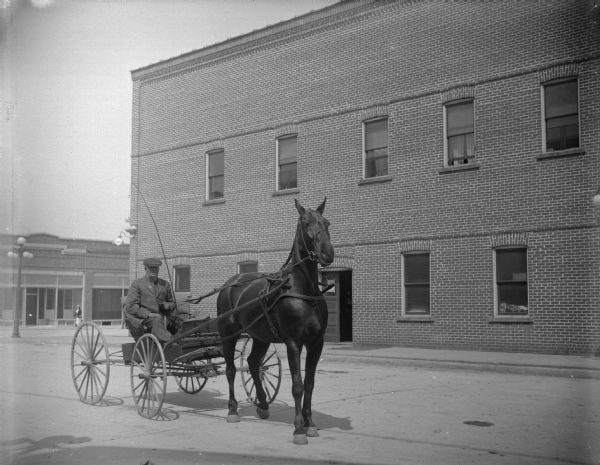 Man with a horse and wagon in town, possibly Henny Berg in front of the Cozy Corner Tavern after the flood of 1911. There is a large lamppost on the corner in the background.