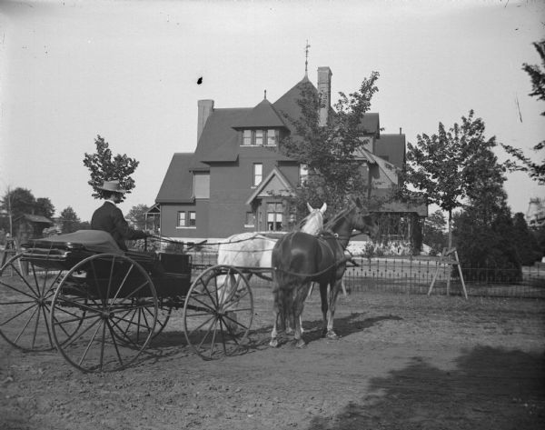 Hugh Price in a top-buggy and two horses posing in front of the home of W.T. Price.