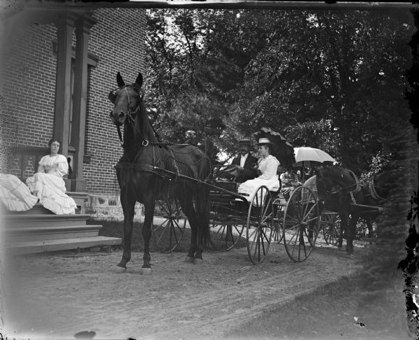 Man and woman in a horse and wagon in front of a building with two women seated on the stoop, probably the Spaulding home, the present location of the Dr. R. Thurou home.
