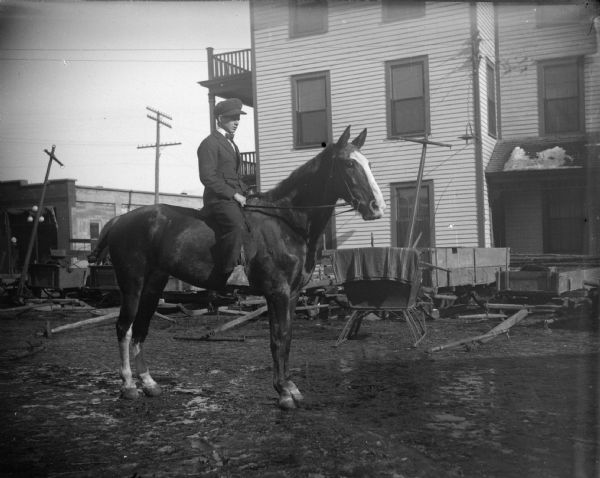 Man posing on a horse in front of the Merchants Hotel.	
