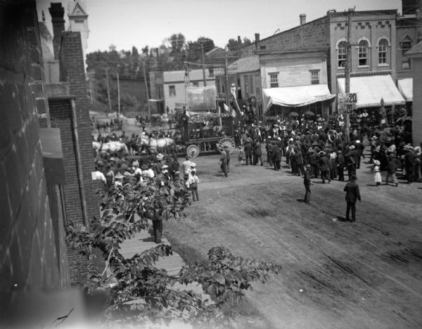 Elevated view towards intersection of a horse-drawn animal cage in a circus parade in town.