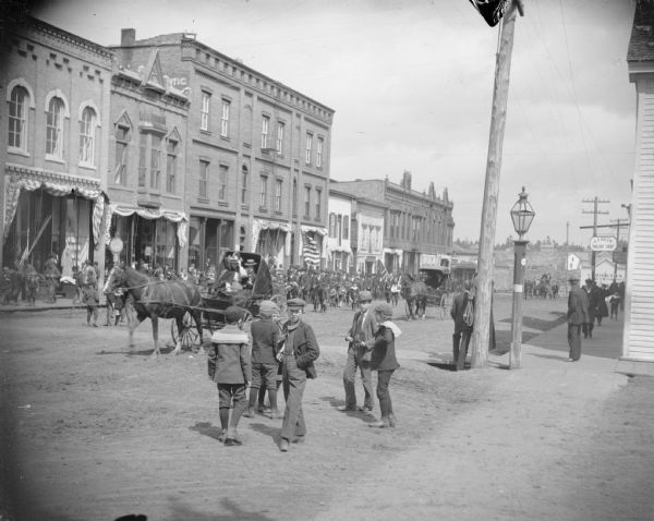 Boys gathered on street to watch a parade through town.