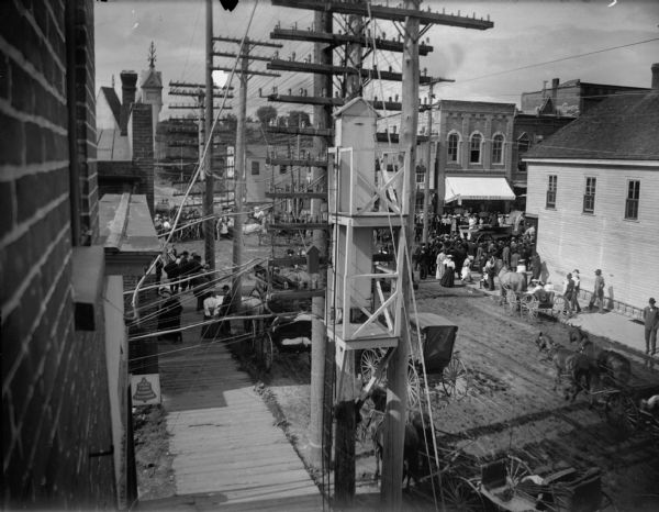 View of crowd watching a parade. Elevated view taken from the Van Schaick studio; the same building housed the telephone exchange.
