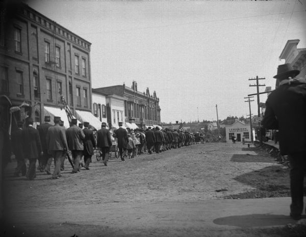 Grand Army of the Republic in Memorial Day Parade, on the north side of Main Street, between First and Water Streets. Iver Erickson's shoemaker shop is at the end of the street. He was an expert, who in addition to making shoes and boots, made steel caulked boots worn by log drivers. His building was destroyed in the 1911 flood.