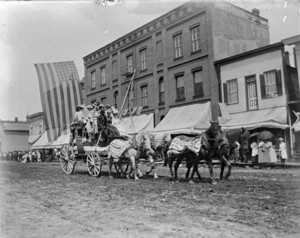 Patriotically decorated stagecoach with a group of people in a parade in town.