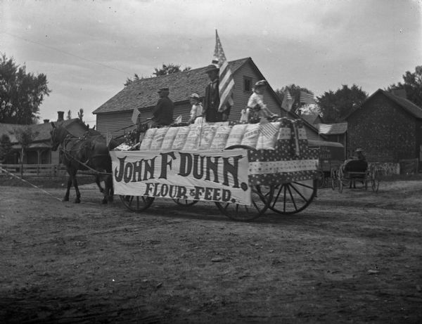 Horse-Drawn wagon for John F. Dunn Flour and Feed, decorated with flour sacks.