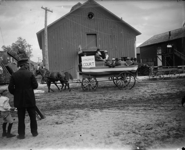 Wagon pulling "Kangaroo Court" through town, probably a promotion for local amateur theatricals. The man on the left is Earl "Dusty" Rhodes, a steam engineer who operated threshing machinery.