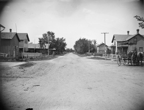 Residential street, with a blacksmith's shop on the left hand side of the street.
