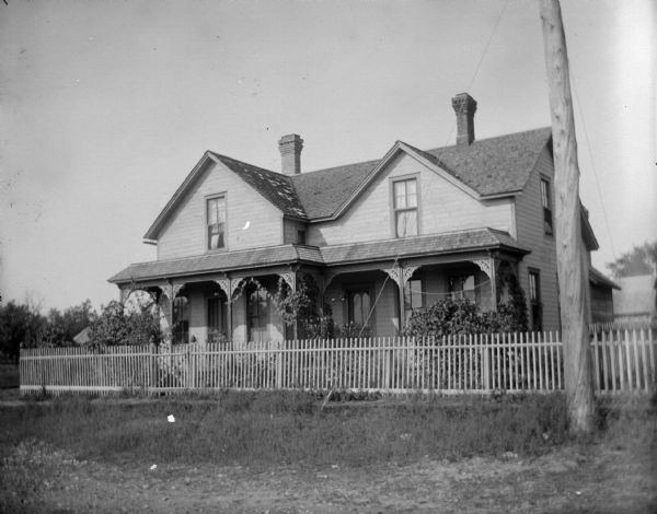 Two-story frame house with a full length porch and picket fence.