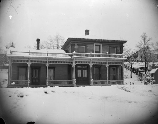 Two-story and one-story frame house with a snow-covered yard.