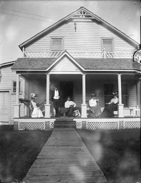 Three women and two men resting on the porch furniture of a town home.