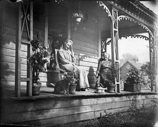 Two women and a cat sitting on the porch of frame house, woman on left probably Mrs. Charles J. Van Schaick.